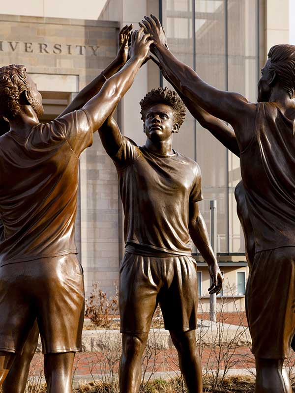 A photo of three bronze statues celebrating together.