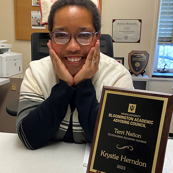 Krystie Herndon poses at her desk with her award.