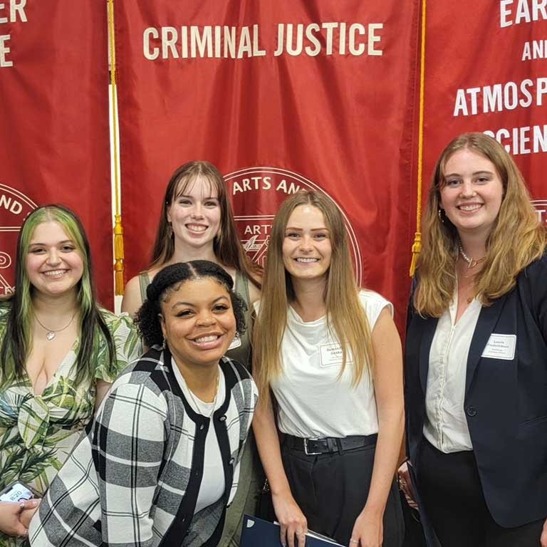 The department's PBK inductees pose together in front of the Criminal Justice graduate banner.
