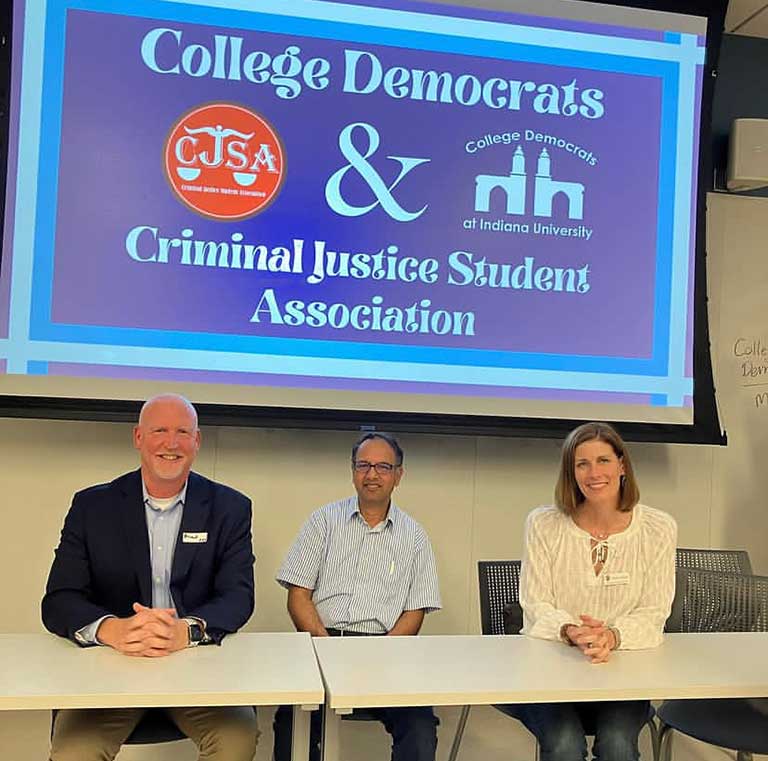 Three people pose in front of the College Democrats and Criminal justice Student Association sign.